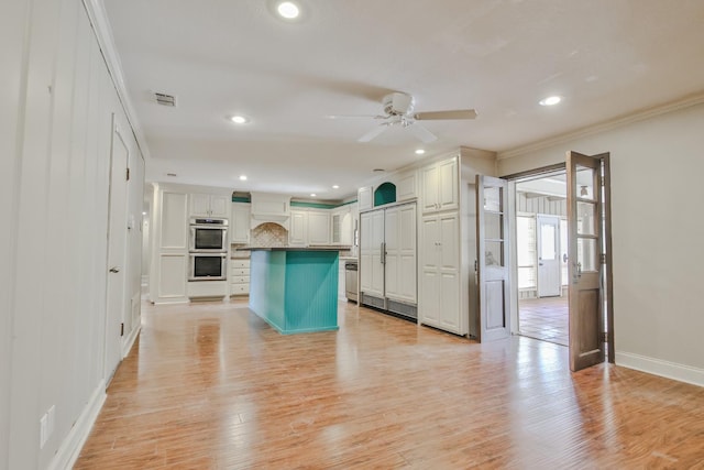 kitchen with crown molding, double oven, light hardwood / wood-style flooring, and white cabinets