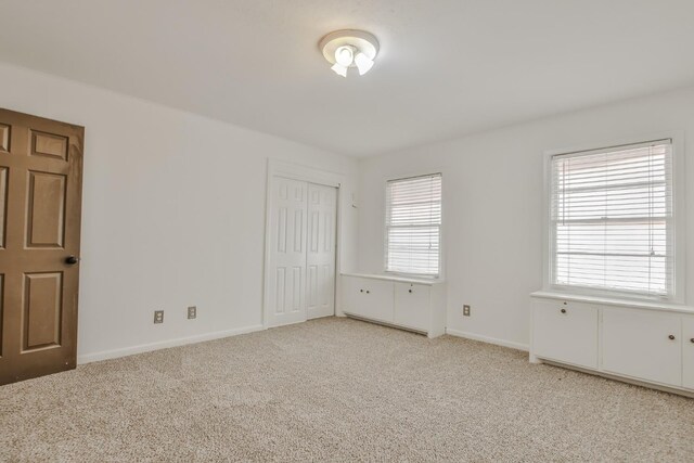 unfurnished bedroom featuring a closet and light carpet