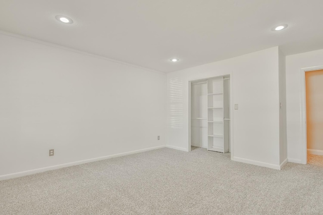 unfurnished bedroom featuring light colored carpet, ornamental molding, and a closet