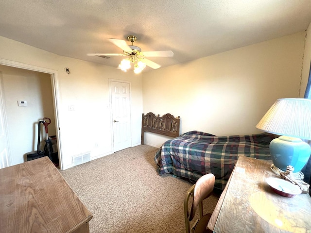 carpeted bedroom featuring ceiling fan and a textured ceiling