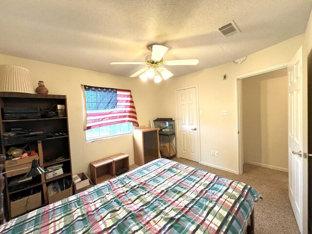 bedroom with ceiling fan, carpet flooring, and a textured ceiling