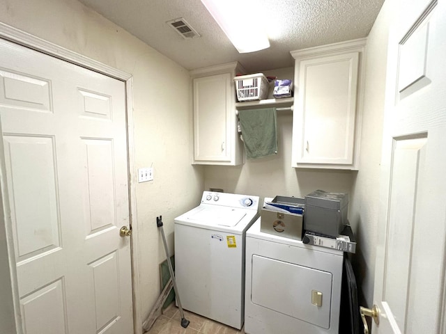 laundry area with separate washer and dryer, cabinets, and a textured ceiling