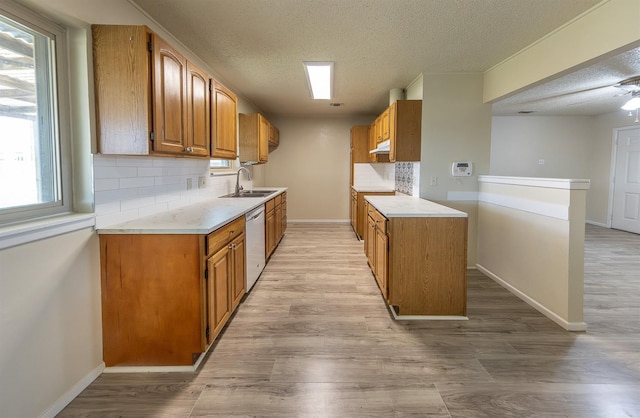 kitchen with sink, tasteful backsplash, a textured ceiling, dishwashing machine, and light hardwood / wood-style floors