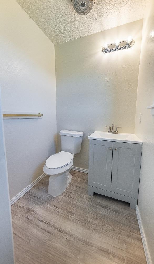 bathroom with vanity, toilet, hardwood / wood-style floors, and a textured ceiling