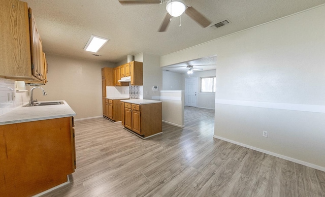 kitchen featuring ceiling fan, sink, light hardwood / wood-style flooring, and a textured ceiling