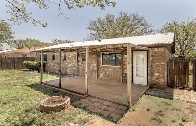 rear view of property with a lawn, a patio area, and a fire pit