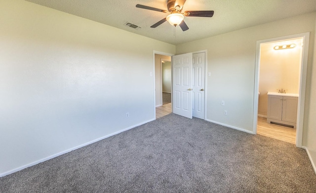 unfurnished bedroom featuring ceiling fan, carpet floors, connected bathroom, and a textured ceiling