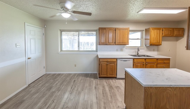 kitchen with sink, tasteful backsplash, a textured ceiling, dishwasher, and light hardwood / wood-style floors