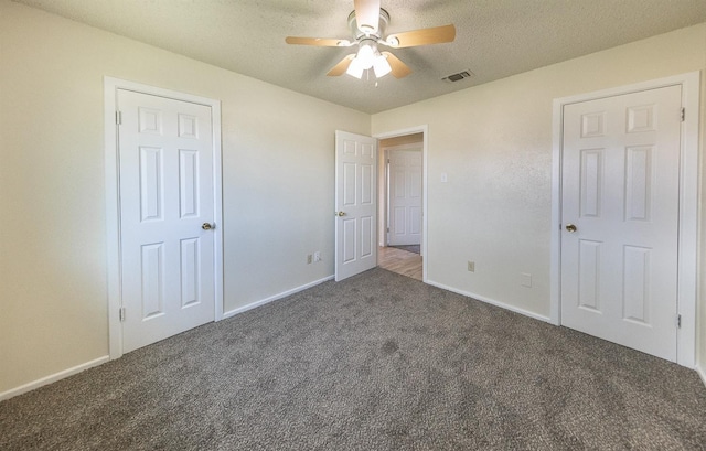 unfurnished bedroom with ceiling fan, dark carpet, and a textured ceiling