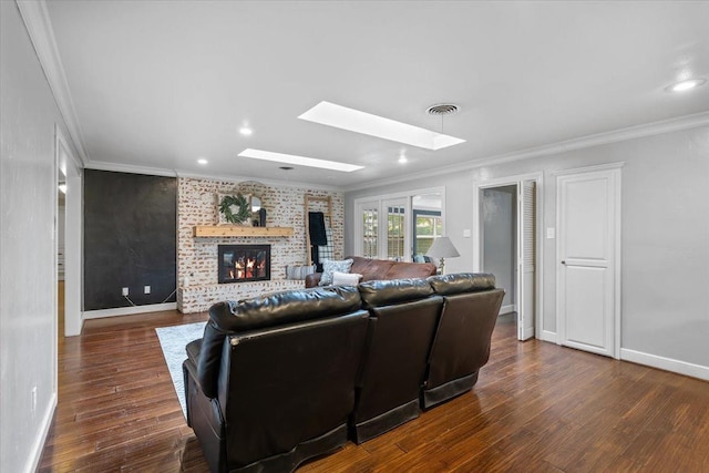 living room with ornamental molding, a brick fireplace, dark hardwood / wood-style flooring, and a skylight