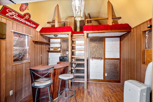 kitchen with hanging light fixtures, wooden walls, dark hardwood / wood-style floors, and a breakfast bar