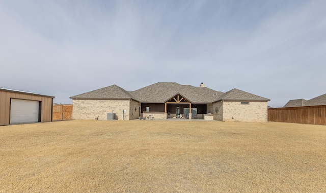 back of house with brick siding, central AC unit, fence, and a shingled roof