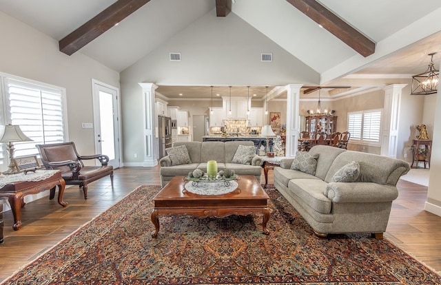 living area featuring decorative columns, visible vents, wood finished floors, a chandelier, and beamed ceiling