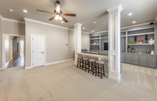 kitchen with carpet, a breakfast bar area, recessed lighting, visible vents, and ornate columns