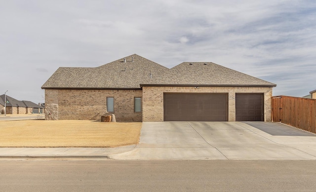 view of front of property with driveway, brick siding, roof with shingles, and an attached garage