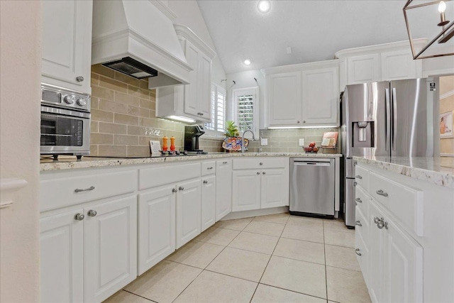 kitchen featuring white cabinetry, custom exhaust hood, lofted ceiling, and appliances with stainless steel finishes