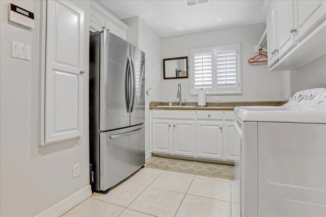 clothes washing area with separate washer and dryer, sink, light tile patterned floors, and cabinets