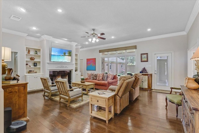 living room with dark wood-type flooring, ceiling fan, ornamental molding, and built in shelves