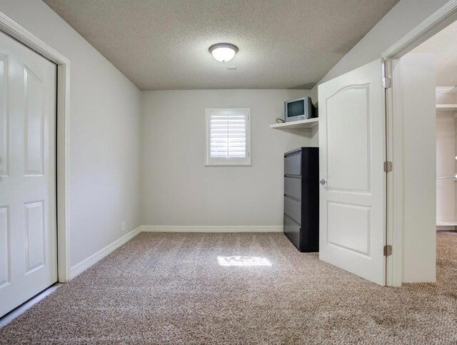 unfurnished bedroom featuring refrigerator, light carpet, and a textured ceiling