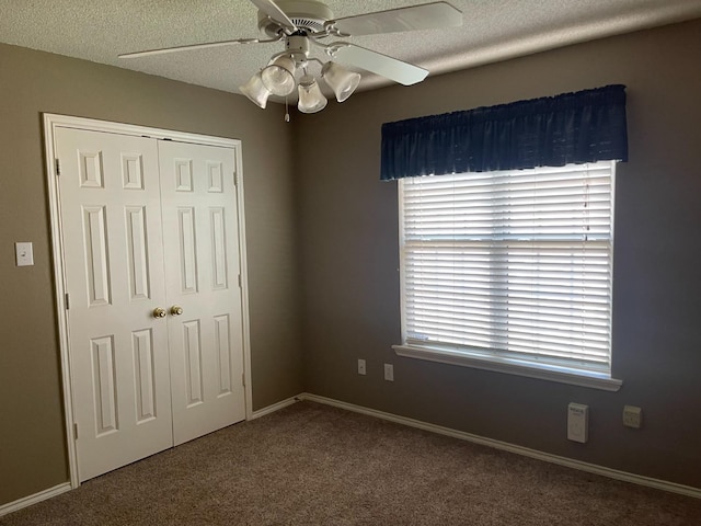 unfurnished bedroom featuring ceiling fan, a closet, a textured ceiling, and carpet flooring