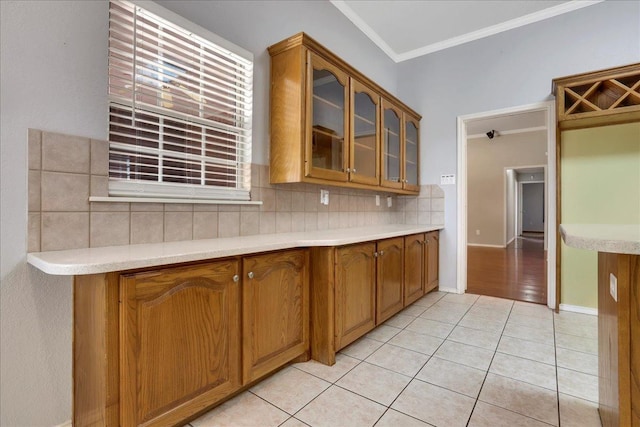 kitchen featuring decorative backsplash, ornamental molding, and light tile patterned flooring