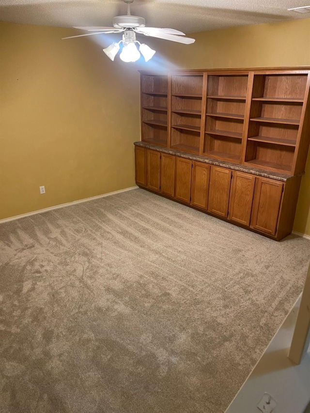 interior space featuring a textured ceiling, light colored carpet, and ceiling fan