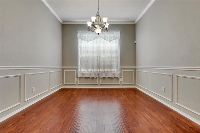 empty room featuring a notable chandelier, hardwood / wood-style flooring, ornamental molding, and a textured ceiling