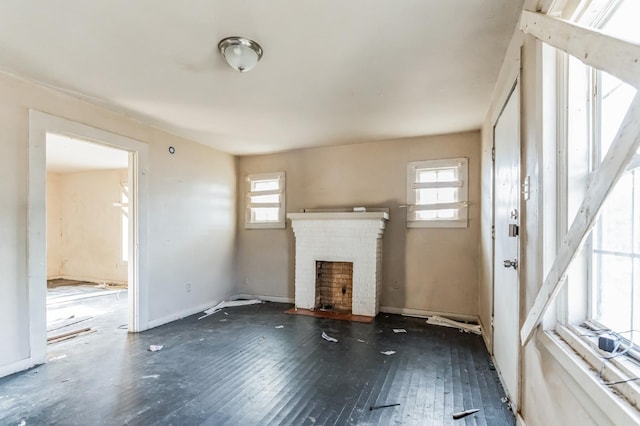 unfurnished living room with dark hardwood / wood-style flooring, a brick fireplace, and a wealth of natural light