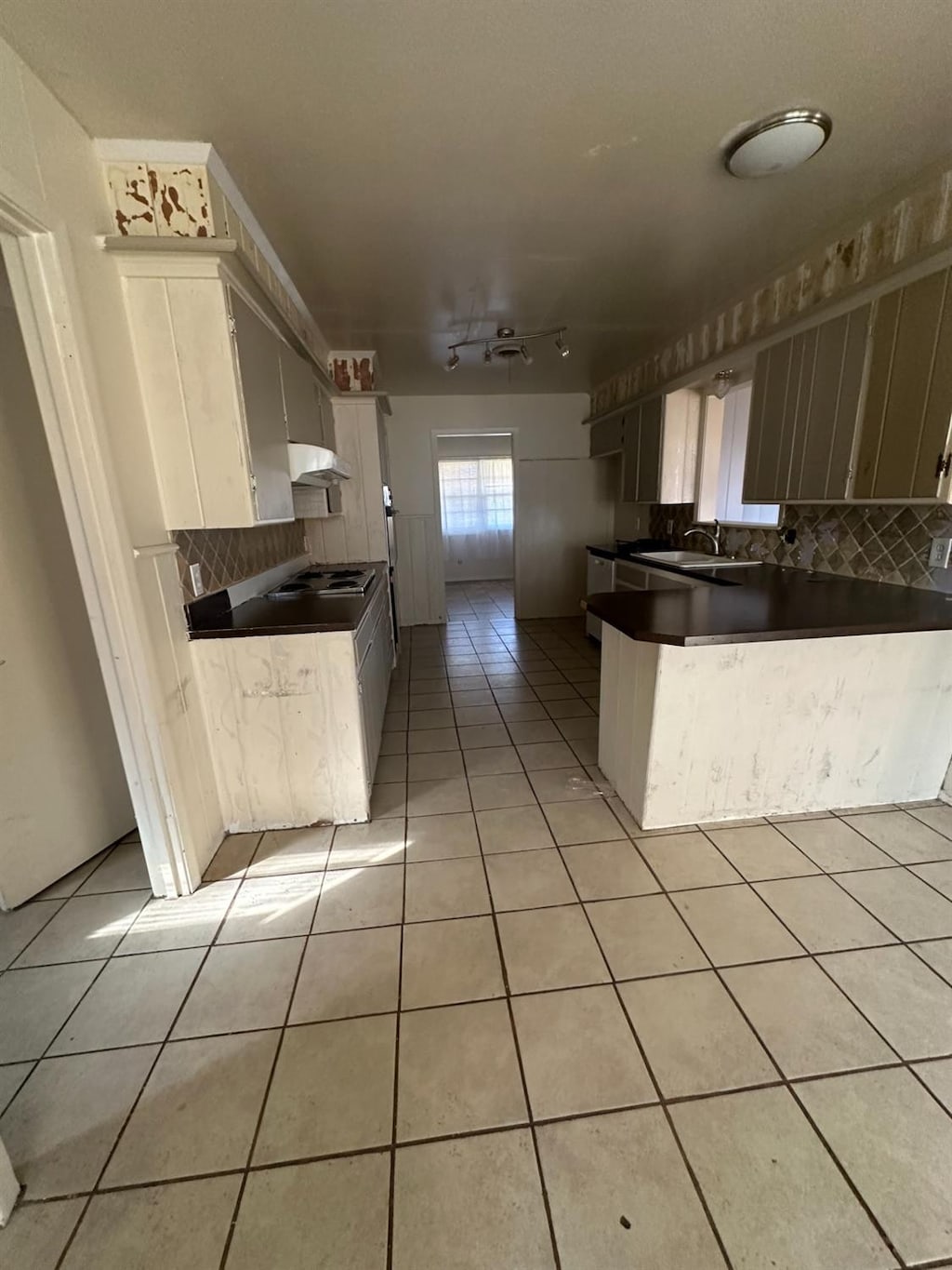 kitchen with light tile patterned floors, sink, white cabinetry, tasteful backsplash, and kitchen peninsula