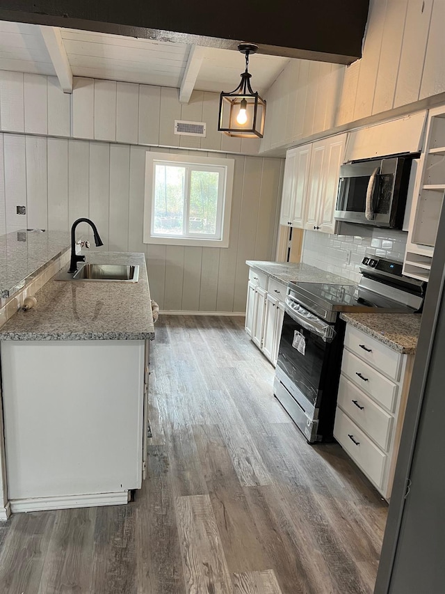 kitchen with sink, stainless steel appliances, light stone countertops, white cabinets, and decorative light fixtures