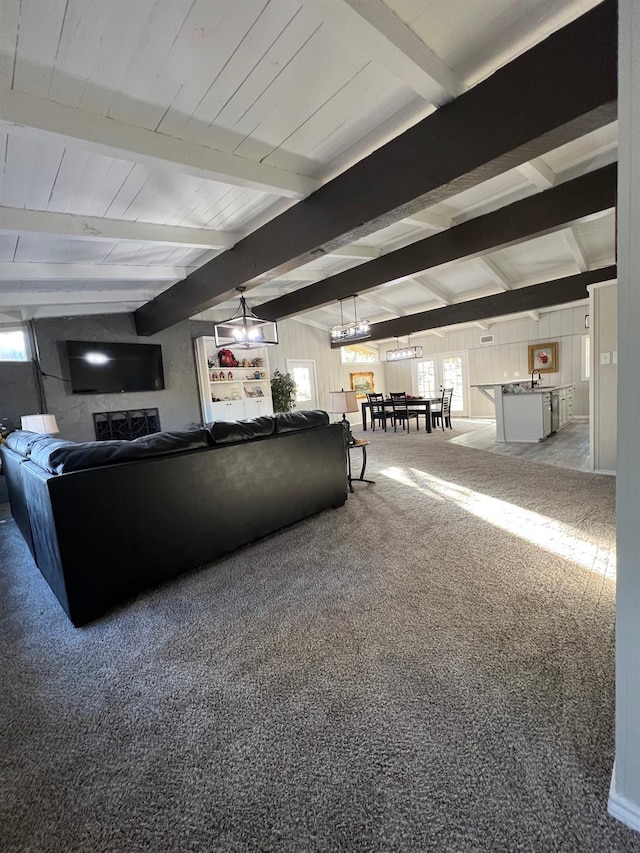 carpeted living room featuring beamed ceiling and wooden walls