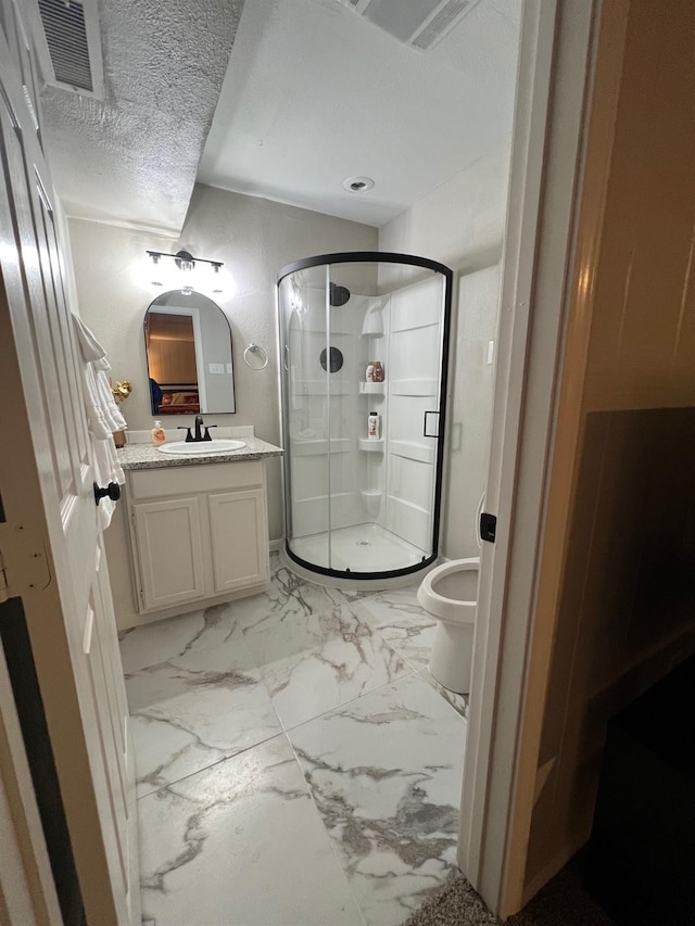 bathroom featuring vanity, toilet, an enclosed shower, and a textured ceiling