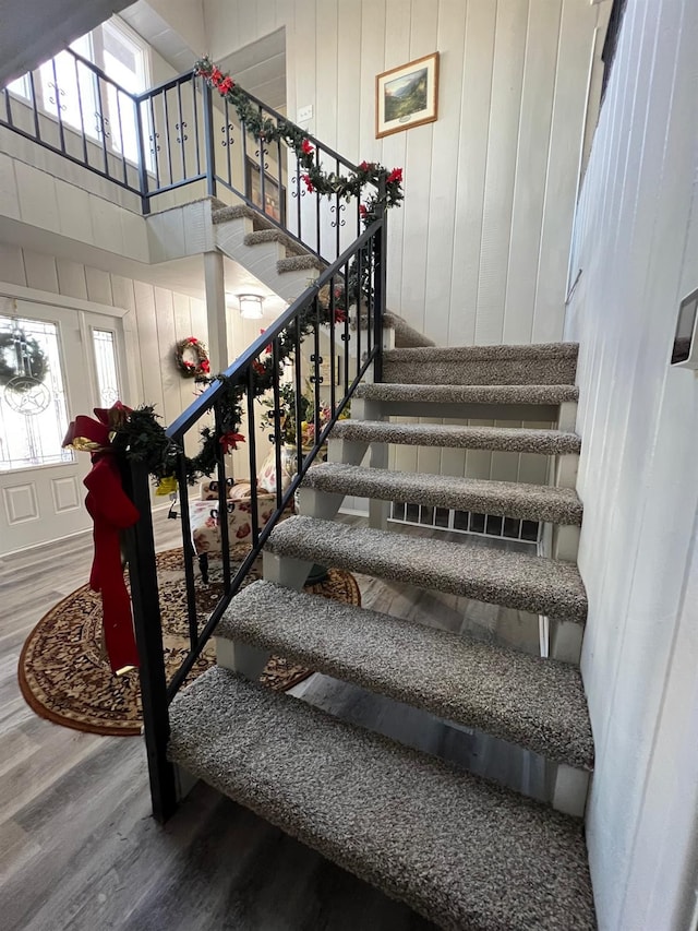 stairs featuring a towering ceiling and hardwood / wood-style floors