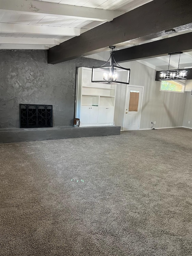 unfurnished living room featuring a large fireplace, beam ceiling, a chandelier, and carpet floors