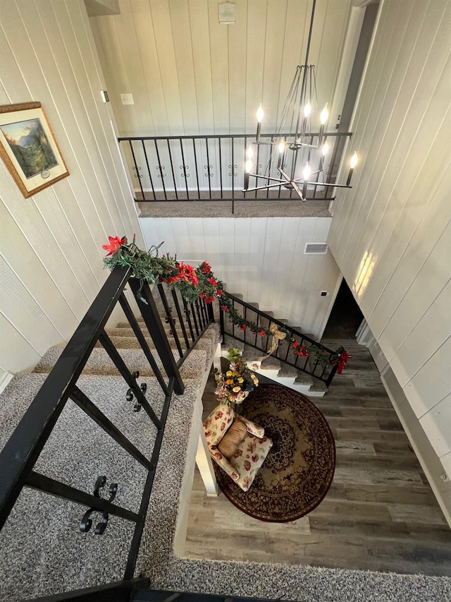 stairway with a notable chandelier, wooden walls, and hardwood / wood-style floors