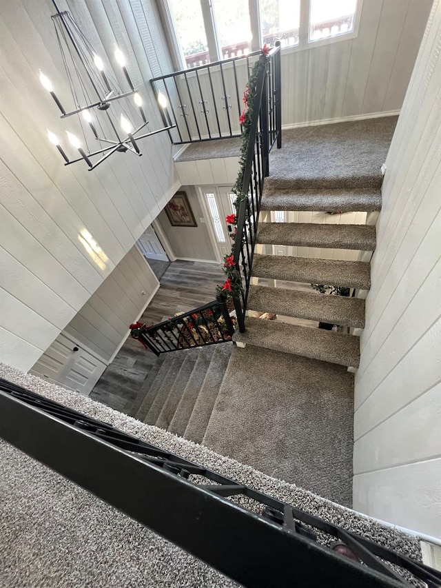 staircase featuring carpet floors and wooden walls