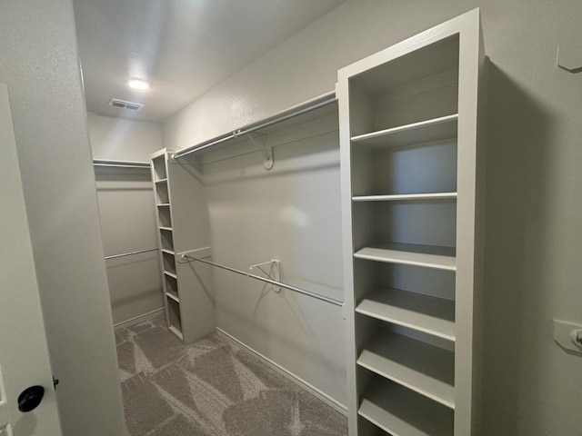 walk in closet featuring dark carpet