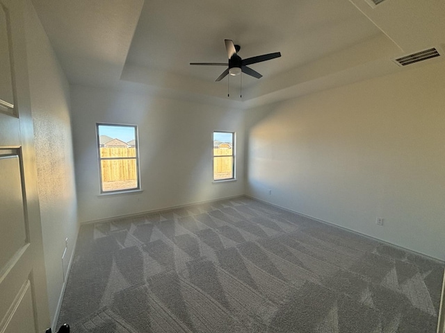 carpeted spare room with ceiling fan and a tray ceiling