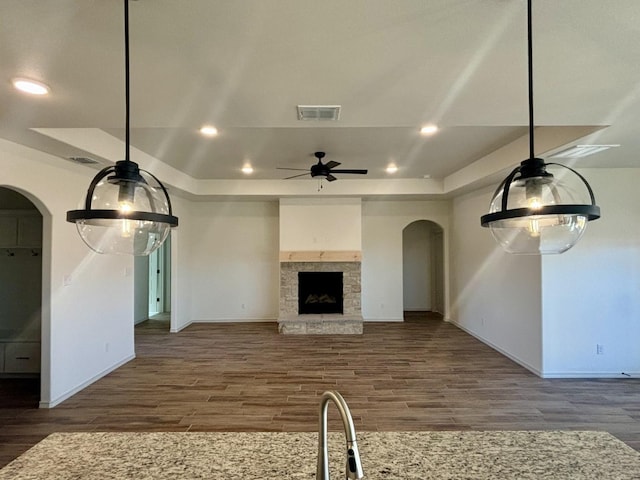 unfurnished living room featuring a fireplace, a tray ceiling, and dark hardwood / wood-style flooring