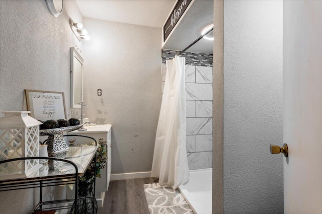 bathroom featuring vanity, a shower stall, wood finished floors, and a textured wall