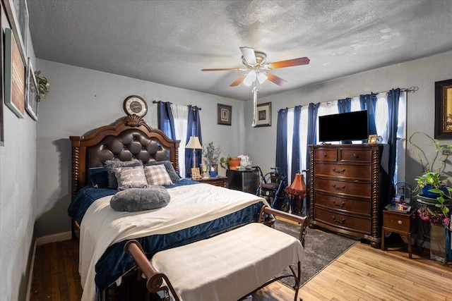 bedroom with a textured ceiling, a ceiling fan, and wood finished floors