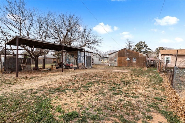 view of yard featuring an outbuilding, a carport, and fence