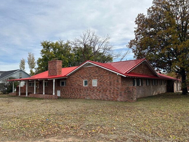 view of side of home featuring a porch and a yard