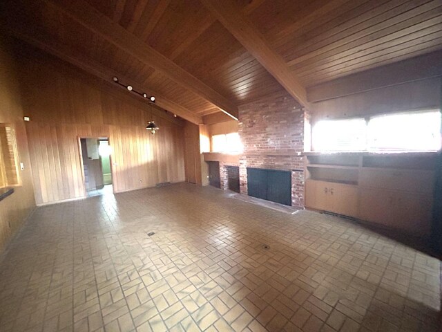 unfurnished living room with vaulted ceiling with beams, wood ceiling, a fireplace, and wood walls