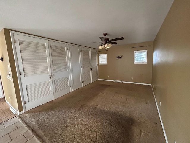 unfurnished bedroom featuring carpet flooring, two closets, and ceiling fan