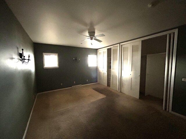 unfurnished bedroom featuring ceiling fan and two closets