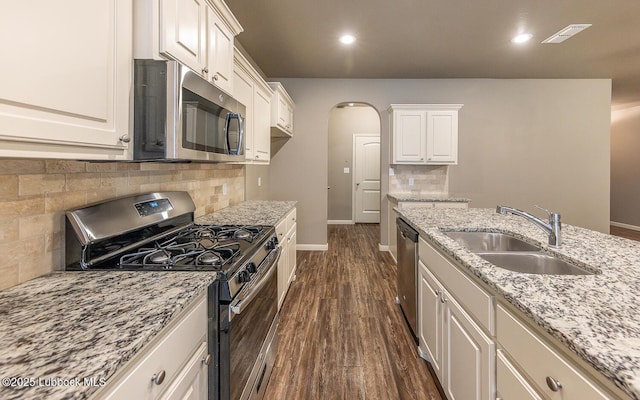 5234 Jarvis St, Lubbock, TX 79416 - kitchen with appliances with stainless steel finishes, arched walkways, dark wood-style floors, light stone countertops, and tasteful backsplash