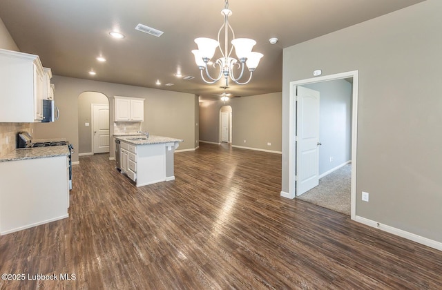 5234 Jarvis St, Lubbock, TX 79416 - kitchen with arched walkways, stainless steel appliances, a chandelier, dark wood finished floors, and a kitchen island with sink