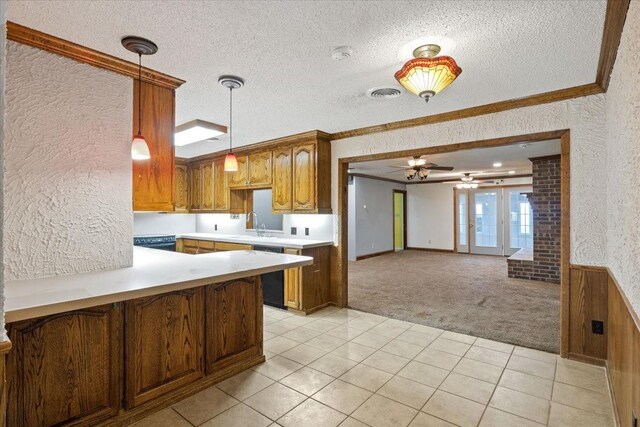 kitchen with crown molding, decorative light fixtures, light colored carpet, kitchen peninsula, and ceiling fan