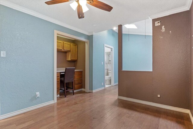 interior space with crown molding, built in desk, light hardwood / wood-style flooring, a textured ceiling, and ceiling fan